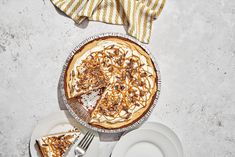 a pie sitting on top of a white plate next to a slice of pie covered in toppings