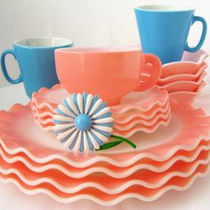 three cups and two saucers sitting on top of each other with matching plates in the shape of waves