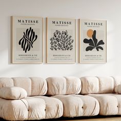 three posters on the wall above a couch in a room with wood flooring and white walls