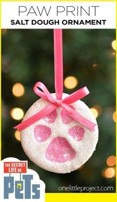 a dog paw ornament hanging from a pink ribbon