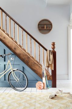 a white bicycle parked in front of a stair case next to a wooden banister