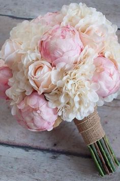 a bridal bouquet with pink and white peonies on a wooden floor in front of a door