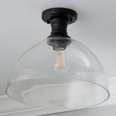 a light fixture with a clear glass dome hanging from it's ceiling, in a white room