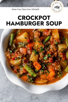 a white bowl filled with crockpot hamburger soup on top of a gray table