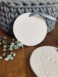 two white ceramic ornaments sitting on top of a wooden table next to some dried flowers