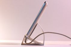 a pen sitting on top of a metal stand in front of a white wall,