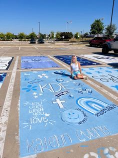 a woman is sitting on the ground in front of some painted parking spots with words