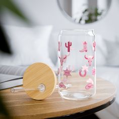 a glass vase with pink and white designs on it sitting on top of a wooden table