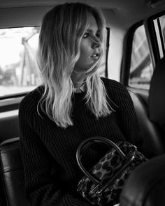 a woman sitting in the back seat of a car with a purse on her lap