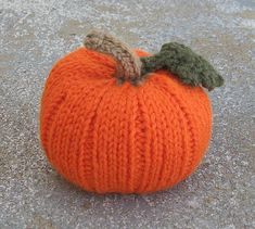 an orange knitted pumpkin sitting on the ground