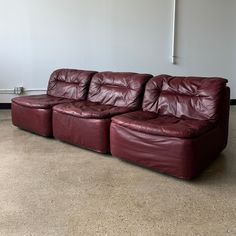 a red leather couch sitting in an empty room