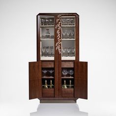 a wooden cabinet with glass doors and wine glasses on it's front door, sitting against a white background