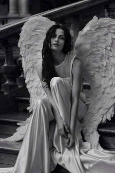 black and white photograph of a woman sitting on stairs with angel wings over her head