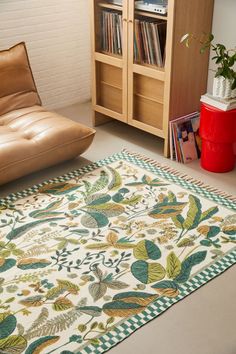 a living room area with a couch, chair and rug on the floor in front of a bookshelf