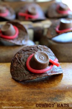 some chocolate cupcakes are sitting on a wooden table and one has a hat on top