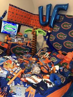 an orange and blue table topped with lots of sports items on top of a bed