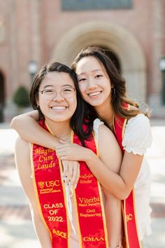 two women hugging each other in front of a building