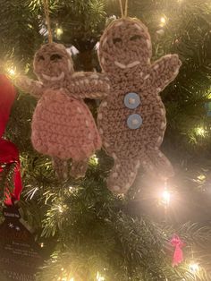 two crocheted teddy bears hanging from a christmas ornament on a tree