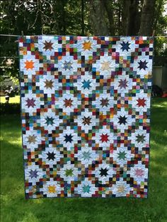 a quilt hanging from a clothes line in the grass