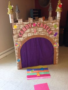 a castle made out of cardboard with candy and candies on the floor next to it