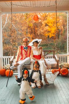 a family dressed up for halloween sitting on a porch swing with their dog and cat costumes