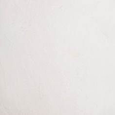 a man riding a snowboard down the side of a snow covered ski slope in front of a white wall