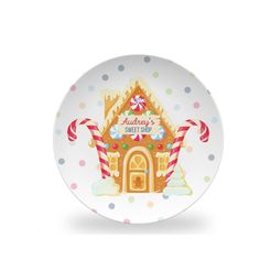 a white plate with a gingerbread house on it and candy canes around the edge