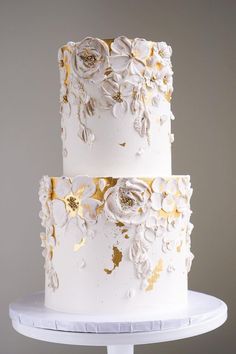 a white and gold wedding cake with flowers on it