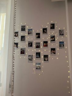 a white wall with many pictures and lights on the wall above it is decorated with string lights