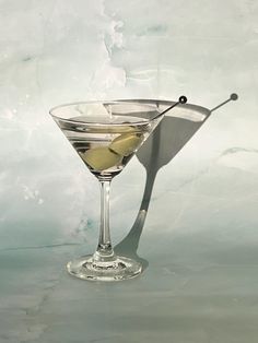 a martini glass with an olive garnish in it