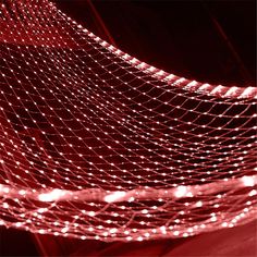 red and white lights are shining on the netted material in this photo, with dark background