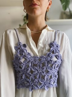 a woman wearing a white shirt and blue crocheted top with an attached collar