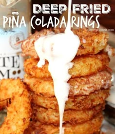 a stack of fried pineapples with white syrup being drizzled over them