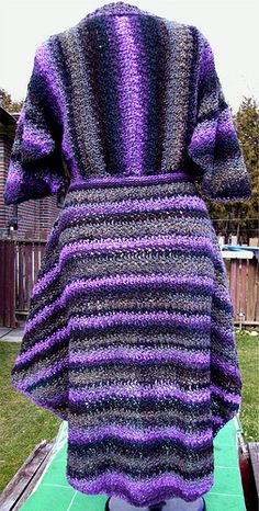 the back of a woman's purple and black striped sweater on a green surface