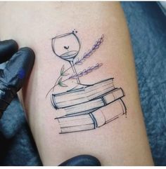 a tattoo with books and a wine glass on it