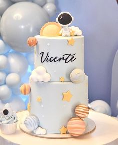 a cake with an astronaut theme on it and balloons in the background for a space themed birthday party