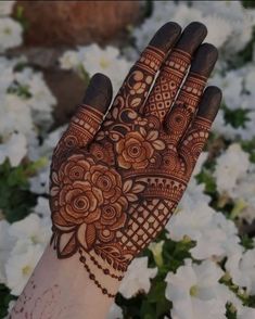 a hand with henna on it and white flowers in the backgroung