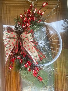 a bicycle wheel decorated with red berries and pine cones is hanging on the front door