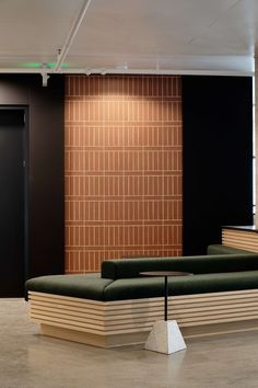 an empty room with two green couches in front of a black wall and door