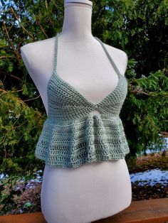 a crocheted top on a mannequin with trees in the background