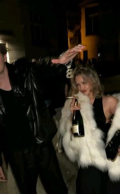 two people dressed in black and white holding wine bottles