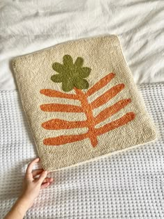 a hand is holding an orange carrot hooked up to a towel on top of a bed