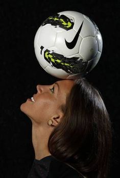 a woman is balancing a soccer ball on her head