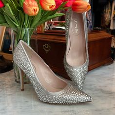 a pair of high heeled shoes sitting next to a vase with tulips