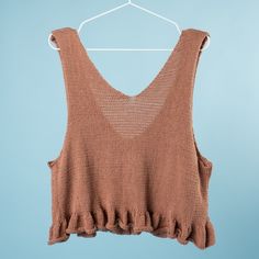 a brown top hanging on a white hanger against a blue background with the back of it's shirt pulled up