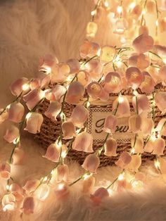 a basket filled with flowers on top of a white fur covered floor next to a string of lights