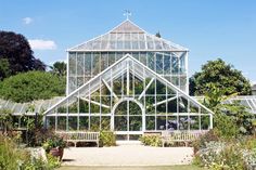 a large glass house in the middle of a lush green field with lots of flowers