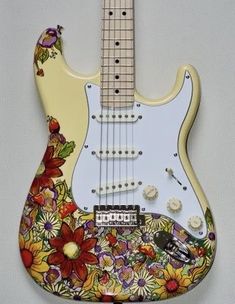 an electric guitar with flowers painted on it's body is hanging from the wall