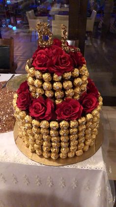 a three tiered cake decorated with gold and red roses