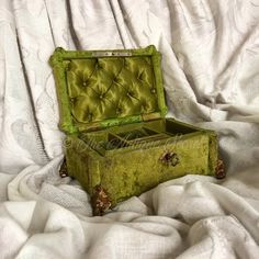 an old green trunk sitting on top of a bed